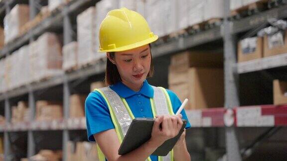 美丽的亚洲工程师女性戴着安全帽和反光背心她检查货架上的商品和用品与平板在仓库物流和商业出口