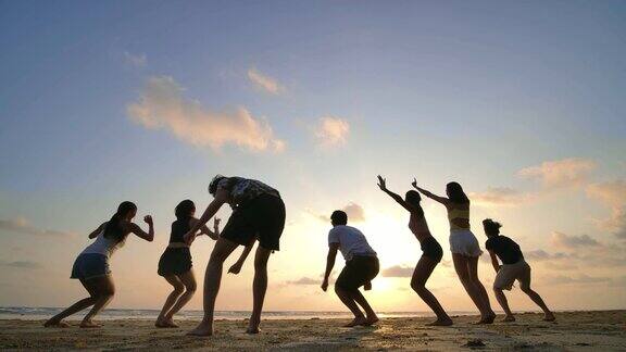 日落时分朋友们在海滩上跳跃的剪影心情愉快4k决议慢动作镜头