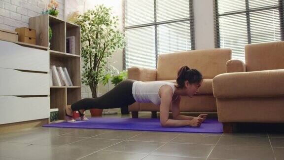 亚洲女性在家锻炼时就在沙发上做平板支撑