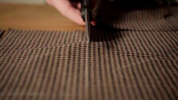 特写裁剪棕色格子羊毛织物行模式在车间里做裁缝和使用缝纫机的年轻人