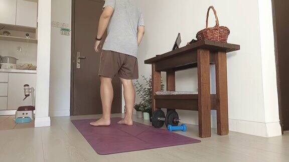 延时亚洲华人中年男子用哑铃锻炼在家锻炼晚上在客厅用数字平板电脑锻炼