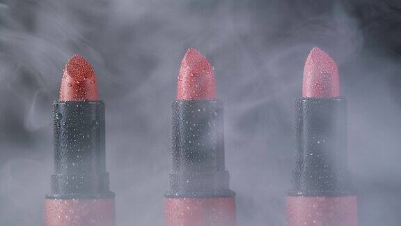 红色的口红化妆近距离黑色背景与烟雾和水滴不同色调的粉红色青铜口红工作室广告宏观美容理念
