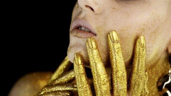 女孩的脸金色的妆容手指上有金色的油漆