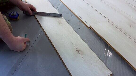 工人在修理期间测量木板并铺设层压板