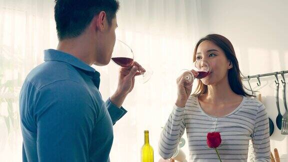 亚洲年轻情侣在情人节举杯畅饮可爱浪漫的新婚男女在家里厨房共进晚餐庆祝结婚纪念日