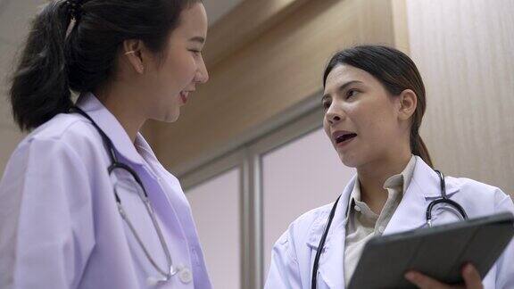 两名亚洲女医生在医院走廊随意交谈