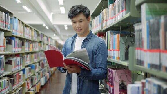 聪明的亚洲人大学学生阅读之间的书架与校园图书馆的copyspace