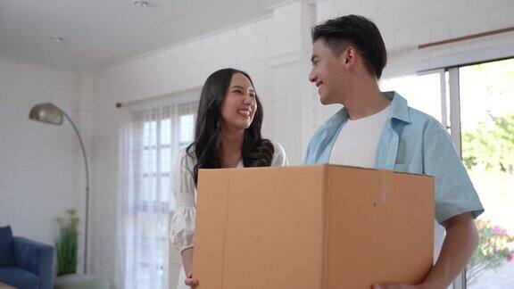 一对亚洲夫妇搬着箱子进入新家