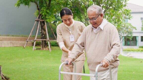 年轻的亚洲女性护理人员教老男性步行使用助行器在公园户外照顾牵手老人