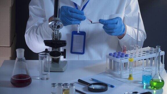 在实验室中处理血液样本的科学家实验室分析员在分析血液载玻片