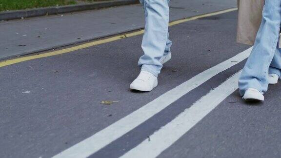 穿着白色运动鞋走在路上的无名人物的腿的特写