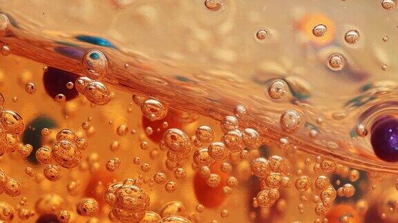 橙色凝胶面乳清带气泡和彩色颗粒在透明的内容中慢慢闪烁美丽