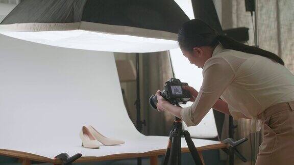 亚洲女摄影师在家庭工作室拍摄女鞋后检查照片
