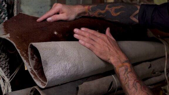 4K特写手手工皮匠谁是抚摸抚摸皮毛上的皮革以选择使用它制作的商品制成的皮革以出售出售的动物皮