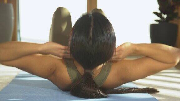 特写:一个年轻的女士在健身锻炼腹部肌肉的背影