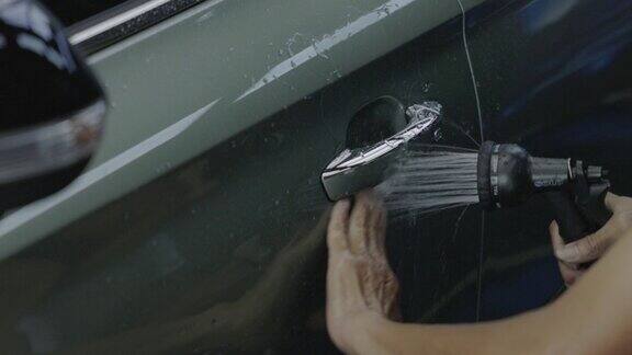 手在车门上喷洒清洁水的特写汽车配件业务