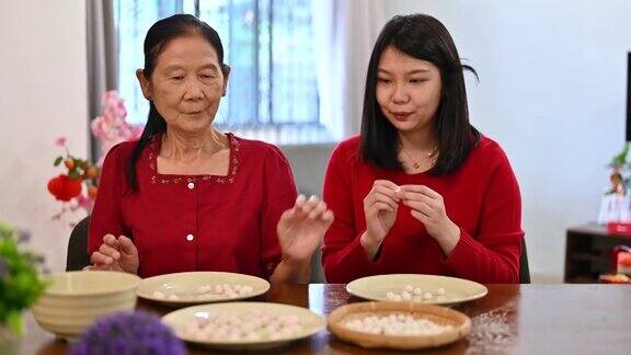 一位亚洲的祖母和她的孙女准备制作汤圆庆祝中国新年