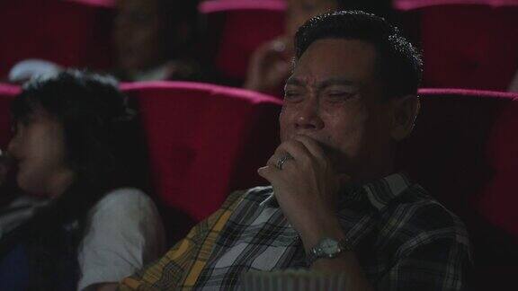 亚洲男人在电影院看浪漫爱情电影时哭了亚洲男人坐在电影院的座位上看悲伤的电影哭了感觉哭