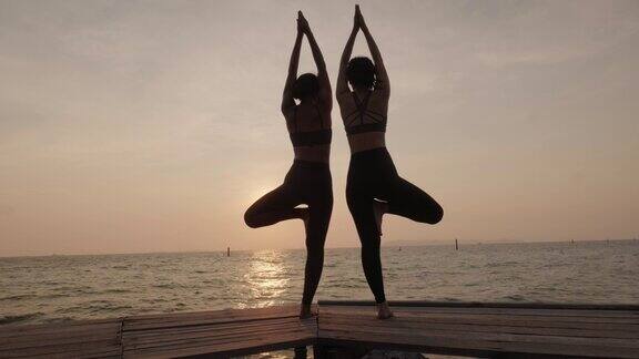 日落时分在海边做瑜伽的女人
