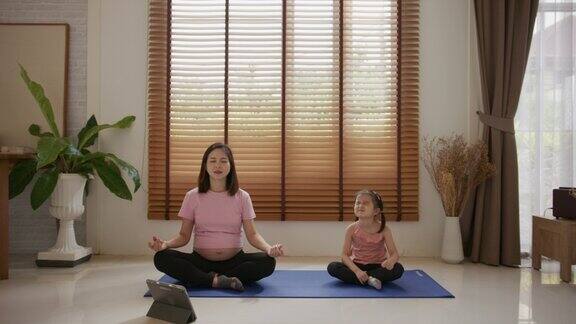 孕妇在家和女儿做瑜伽
