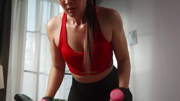 穿着运动服的迷人亚洲女性在家里锻炼时尝试力量训练