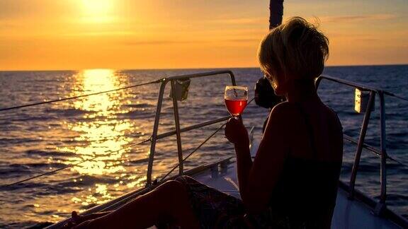 在夕阳下航行时喝葡萄酒的女士