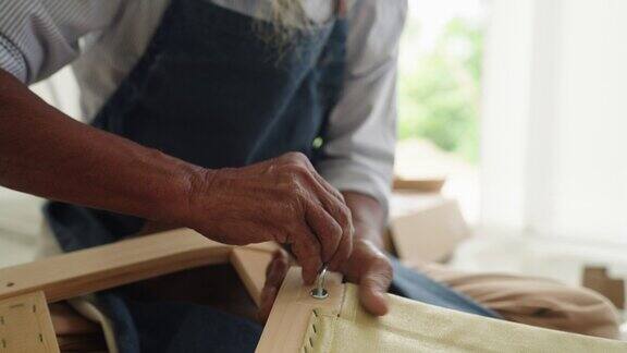 特写:一位白发的亚洲老人早上在家组装椅子胶合板