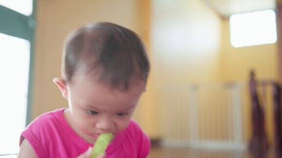 小可爱的亚洲男婴的特写脸用手拿起番石榴水果进嘴里坐在家里放松的时候