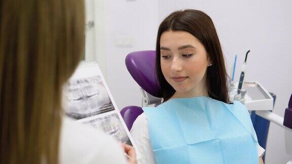 女牙医展示牙齿的x光片或照片现代牙科诊所女医生和病人谈话讨论治疗方案