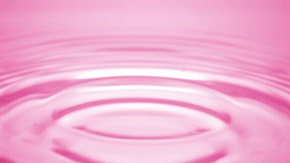 水滴落在粉红色的流体表面形成水环