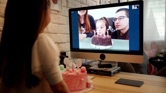 生日女孩吹生日蜡烛而她的家人通过视频应用程序唱她的生日歌