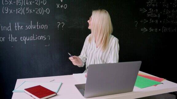 快乐的老师坐在教室的黑板前上在线数学课