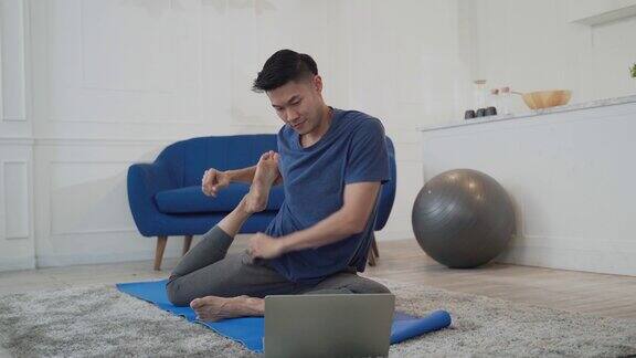 年轻的亚洲男子在家里做放松练习瑜伽