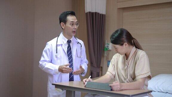 年轻的亚洲男医生走进他的病人的房间和她谈话