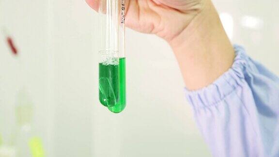 手里拿着一个带着绿色液体的试管