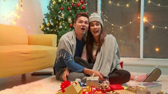 年轻的亚洲夫妇在庆祝冬季节日期间在家里看电视电影