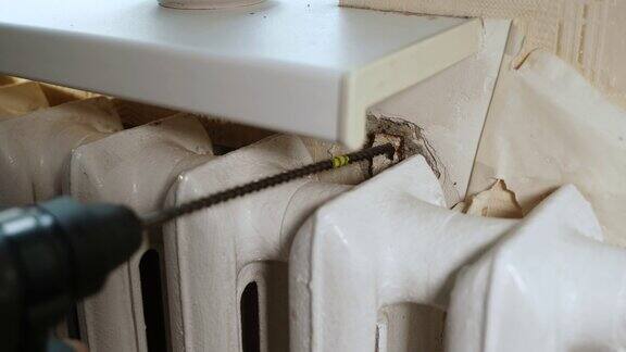 穿孔器在生锈的暖气片支架上钻混凝土壁