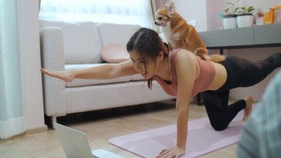 年轻的亚洲女性在家里的客厅练习瑜伽