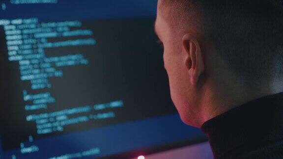 软件开发人员在项目上工作的后视图一个黑客在霓虹灯下在电脑上工作的肖像