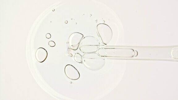 透明的化妆品凝胶液血清与分子气泡油在移液管滴在白色背景上天然有机化妆品医药的宏观镜头生产特写慢动作