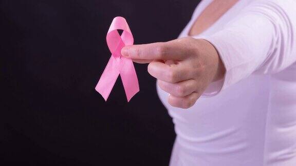 白人妇女手持粉红癌症意识丝带黑色背景的中段视频