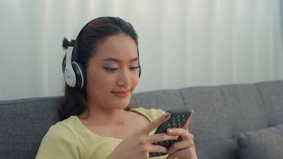 女人戴着耳机在家里听着音乐唱着快乐的假期