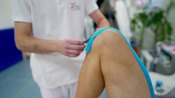 理疗师在病人的膝盖上贴运动胶带