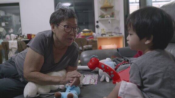 亚洲男孩和奶奶在沙发上玩玩具