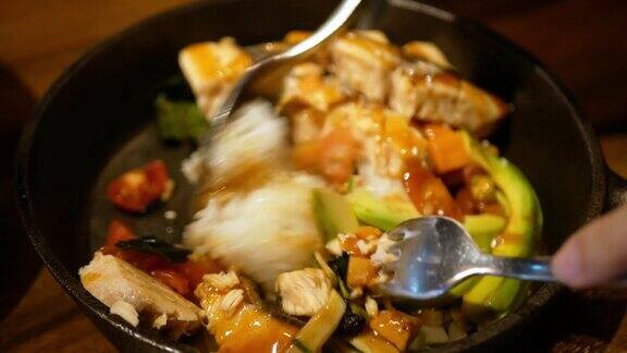 把自制的酱汁倒进夏威夷风格的碗里里面有米饭烤鲑鱼鳄梨和豌豆