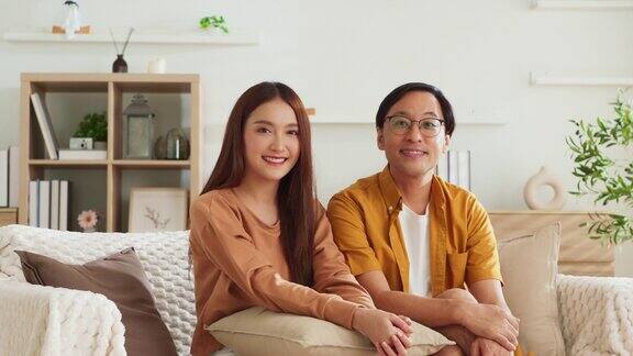幸福平和随意放松的亚洲已婚夫妇呆在家里良好的亚洲夫妻氛围在家里客厅的沙发沙发上一起聊天温馨的家庭理念