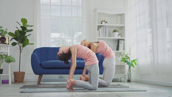 母亲和女儿在家里练习瑜伽轮式或桥式