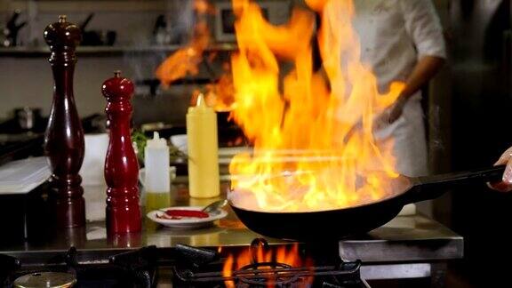 两个厨师拿着燃烧的平底锅用火煎虾的过程