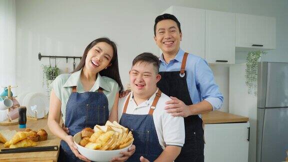 亚洲幸福家庭烘焙面包店唐氏综合症的儿子在厨房美丽慈爱的父母照顾和教导患有自闭症或有特殊需要的年轻人在家做饭