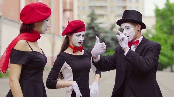 三个滑稽的哑剧演员在城市的街道上表演